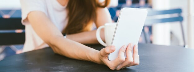 Attractive beautiful happy young Asian woman taking a selfie using a smart phone at cafe