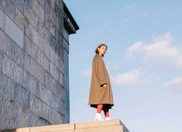 Free photo an attractive beautiful young woman standing in front of wall against sky