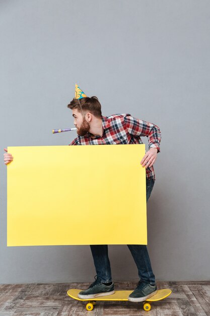 Attractive birthday man on skateboard holding blank board