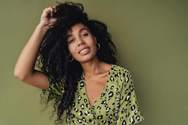 Attractive black african american woman posing in stylish green dress isolated on green background