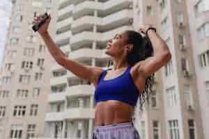 Free photo attractive black african american woman in sport fitness outfit on rooftop making work out
