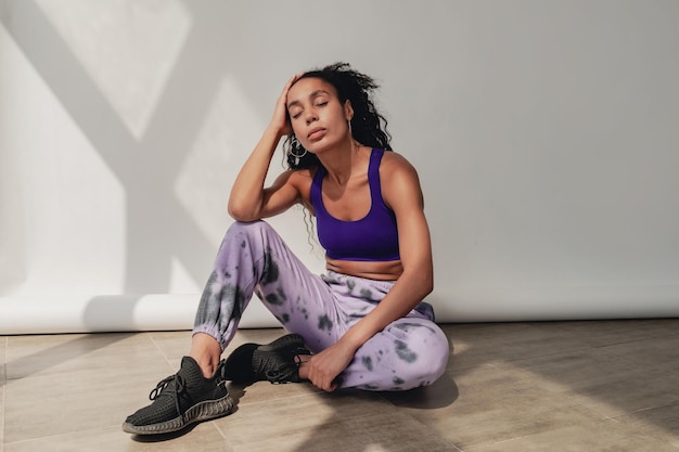 Attractive black african american woman in stylish hipster fitness outfit on background