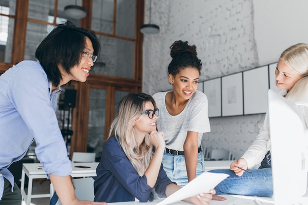 Attractive black woman with short hair joking with friends at their workplace during break