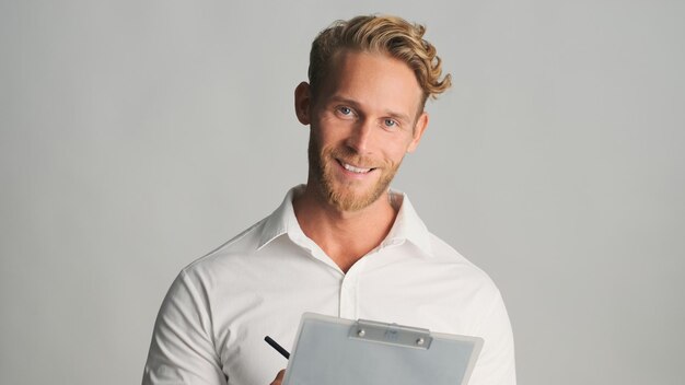 Attractive blond bearded businessman in shirt looking happy working with documents isolated on white background Successful man