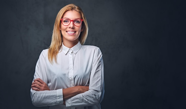 Attractive blond business woman in a white shirt, eyeglasses and crossed arms over grey background.