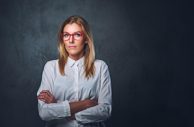 Attractive blond business woman in a white shirt, eyeglasses and crossed arms over grey background.