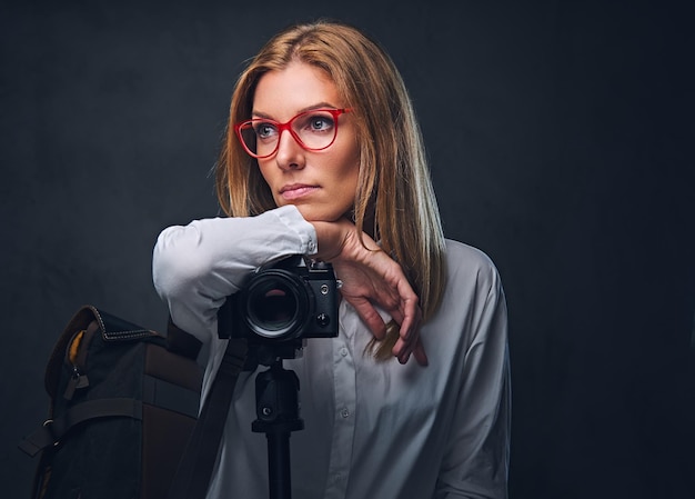 Una fotografa bionda attraente che scatta foto con una fotocamera professionale su un treppiede.