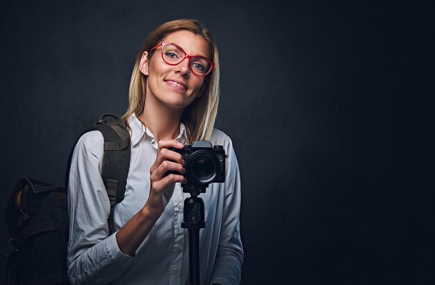 An attractive blond female photographer taking pictures with professional camera on a tripod.