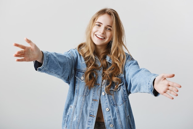 Free photo attractive blond girl smiling happy and spread hands sideways for hug, embracing or taking something