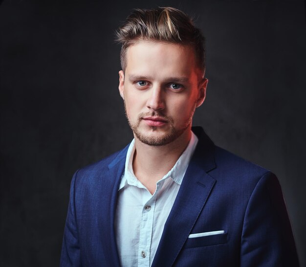 An attractive blond male dressed in a suit over dark grey background.