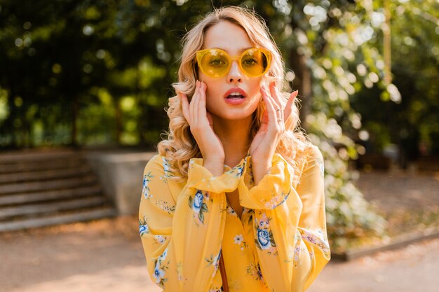 Attractive blond stylish smiling woman in yellow blouse wearing sunglasses