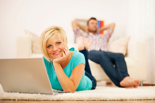 Attractive blonde woman using computer on the carpet