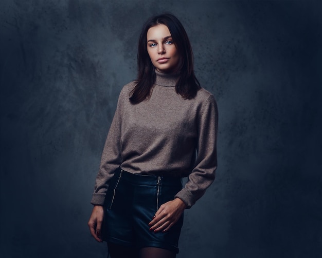 Free photo an attractive brunette female dressed in a long neck brown jacket over grey background.