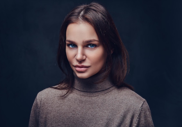 Free photo an attractive brunette female dressed in a long neck brown jacket over grey background.