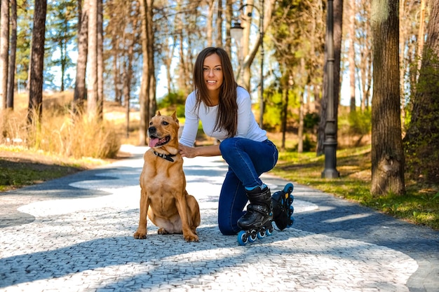 春の自然パーの道路で彼女の犬と一緒にポーズをとる魅力的なブルネットの女性。