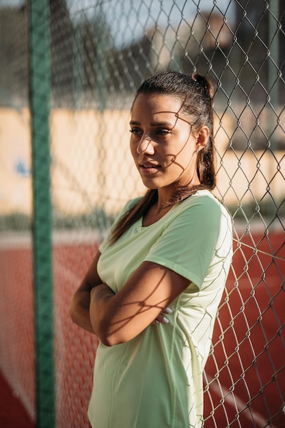 Brunette attraente che si appoggia sul recinto di collegamento a catena all'aperto