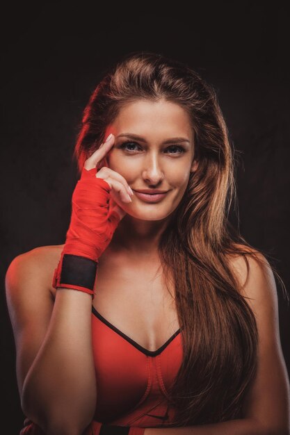 Attractive brunette in red gloves and sport bra is posing for photographer at studio.