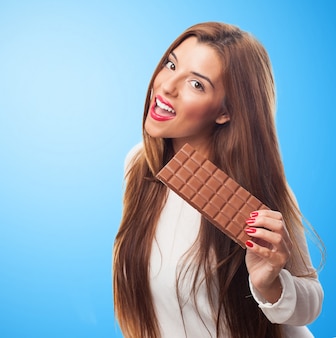 Brunette attraente con la barra di cioccolato.