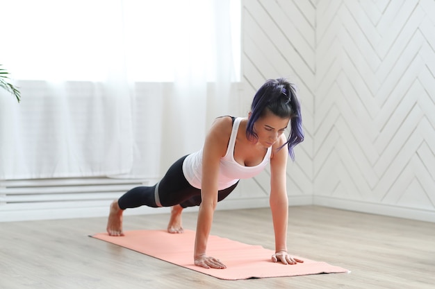 Attractive brunette woman doing yoga at home.