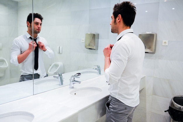 Attractive businessman looking at himself in the mirror