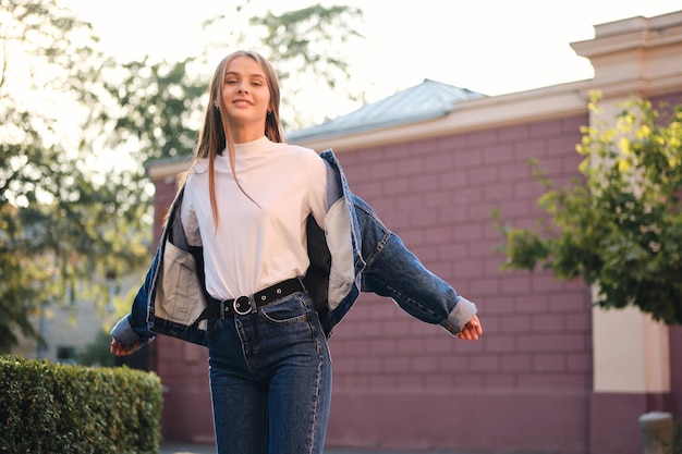 Attractive carefree stylish casual girl in denim jacket dreamily looking in camera outdoor