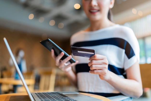 クレジットカードデータとラップトップテクノロジーのライフスタイルを使用して、魅力的なカジュアルでスマートなアジアの女性女性のオンラインショッピングをオンラインで購入