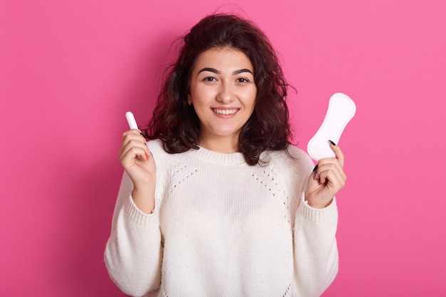 Attractive Caucasian woman holding cotton tampon and sanitary napkin