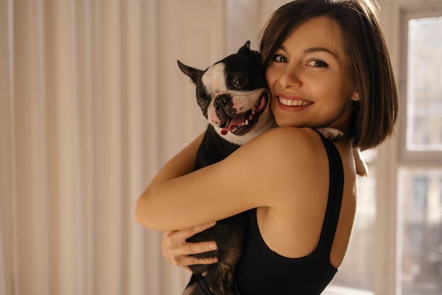Free photo attractive caucasian young girl looks at camera and holds pet close to her concept of friendship between man and animals