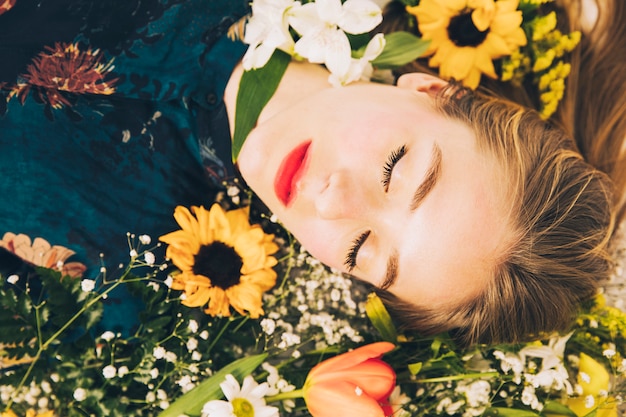 魅力的な魅力的な女性は花の間に横たわる