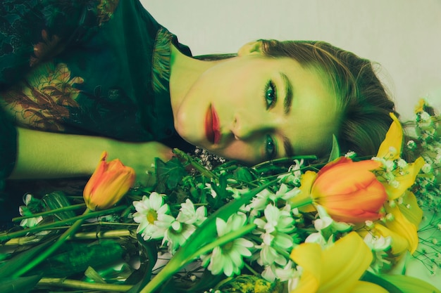Привлекательная очаровательная женщина лежит с букетом цветов в зелени