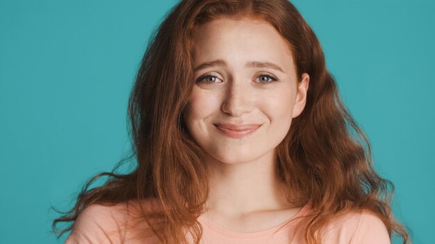 Attractive cheerful redhead girl joyfully looking in camera over colorful background