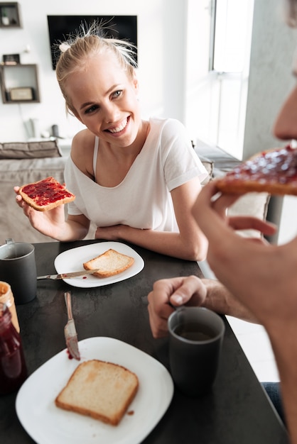 Attractive cheerful woman looking at her man while they eating breakfast