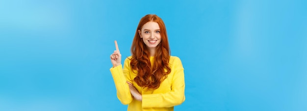 Attractive confident and charismatic caucasian redhead female in yellow sweater showing number one o