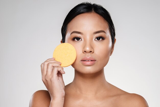 Attractive confident lady cleaning her face with cotton pad