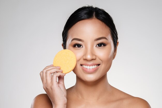 Attractive confident lady cleaning her face with cotton pad