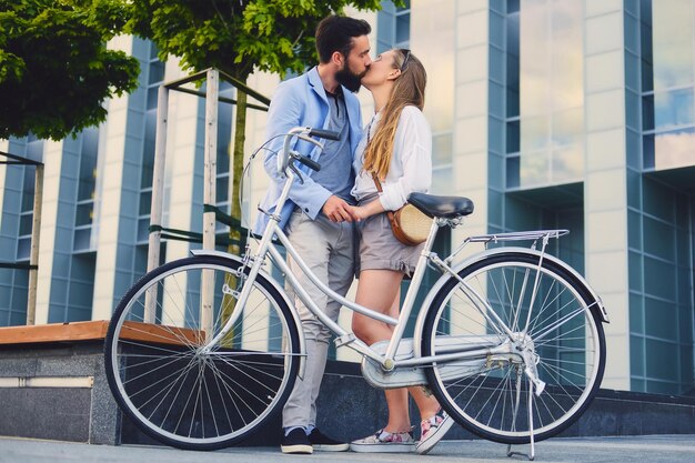 街で自転車に乗った後のデートで魅力的なカップル。男性が女性にキスをします。