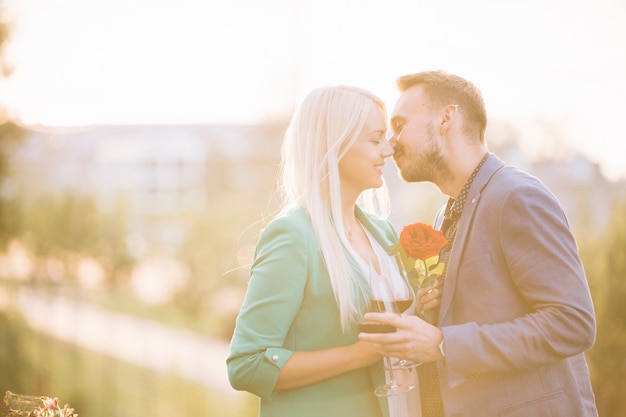 An attractive couple holding wineglasses kissing each other