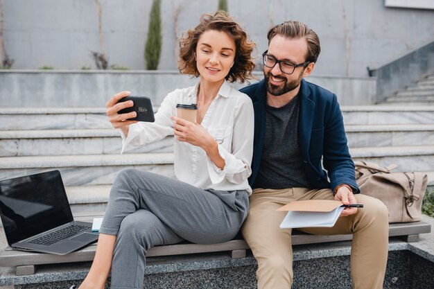 Attractive couple of man and woman sitting on stairs in urban city center