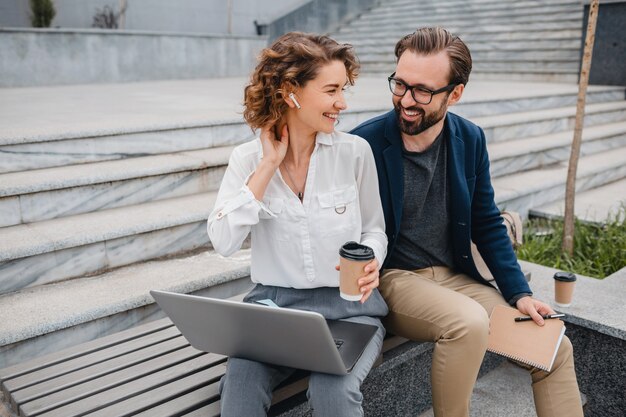 Attractive couple of man and woman sitting on stairs in urban city center