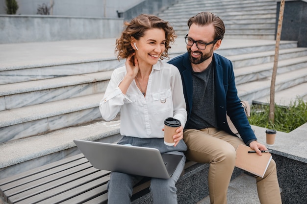 Attractive couple of man and woman sitting on stairs in urban city center