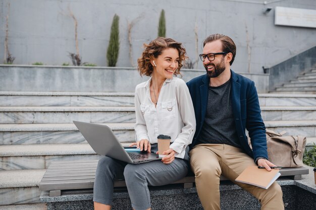 Attractive couple of man and woman sitting on stairs in urban city center