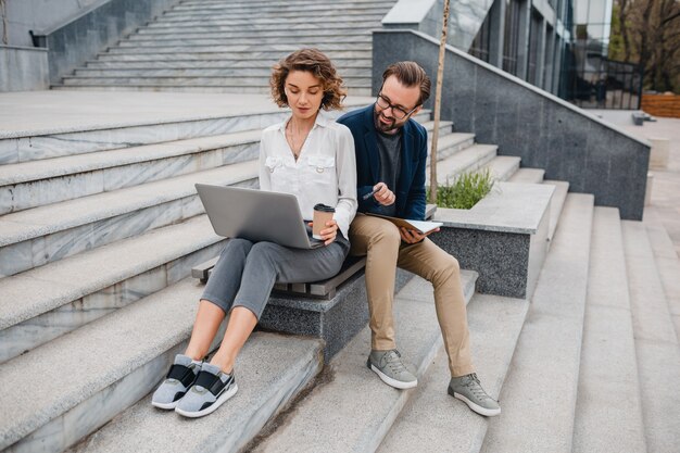 Attractive couple of man and woman sitting on stairs in urban city center