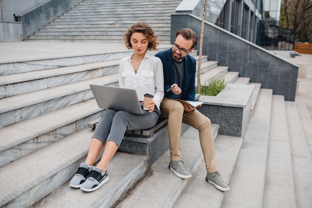 Attractive couple of man and woman sitting on stairs in urban city center