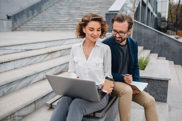 Attractive couple of man and woman sitting on stairs in urban city center