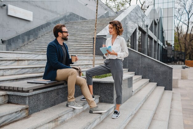 Attractive couple of man and woman sitting on stairs in urban city center