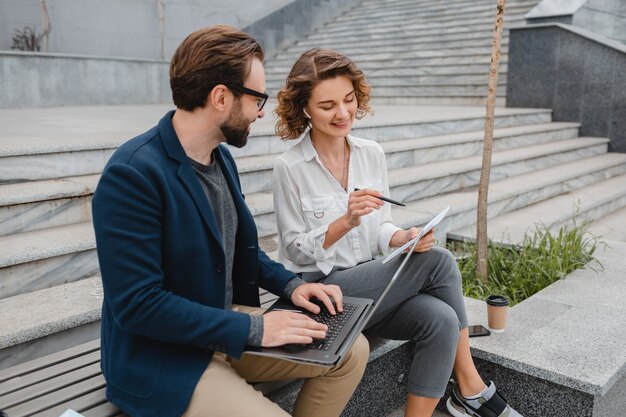 Attractive couple of man and woman sitting on stairs in urban city center