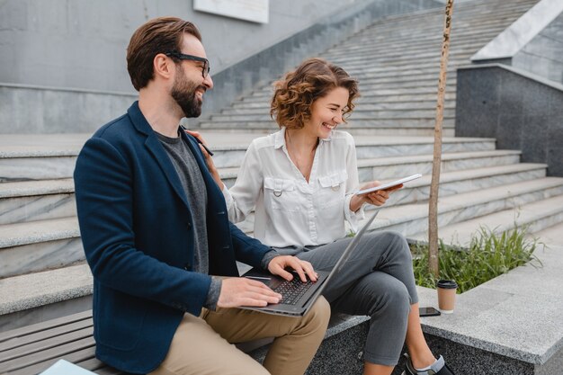 Attractive couple of man and woman sitting on stairs in urban city center