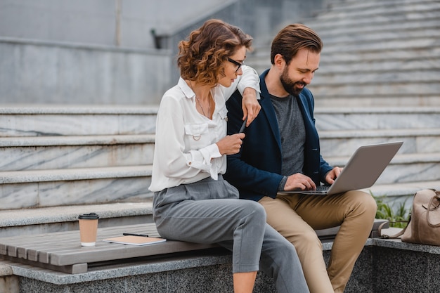 Attractive couple of man and woman sitting on stairs in urban city center