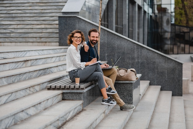 Attractive couple of man and woman talking sitting on stairs in urban city center