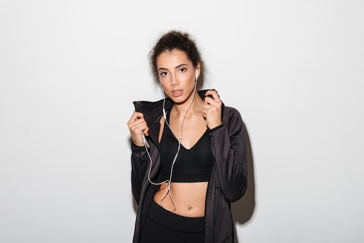 Free Photo attractive curly brunette fitness woman listening music